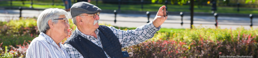 Un matrimonio mayor sentado en un parque se hace un seflie