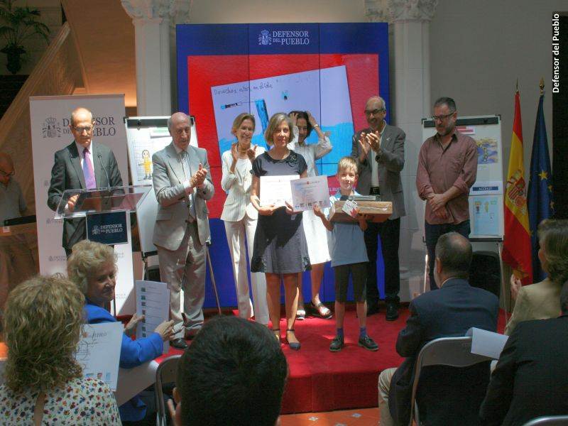 Uno de los ganadores y su profesora recoge su premio ante la mirada del jurado del Concurso de Dibujos