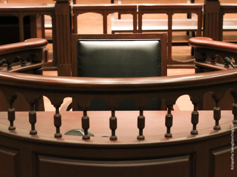 Silla con respaldo cuero rodeada barandilla donde se sienta declarante