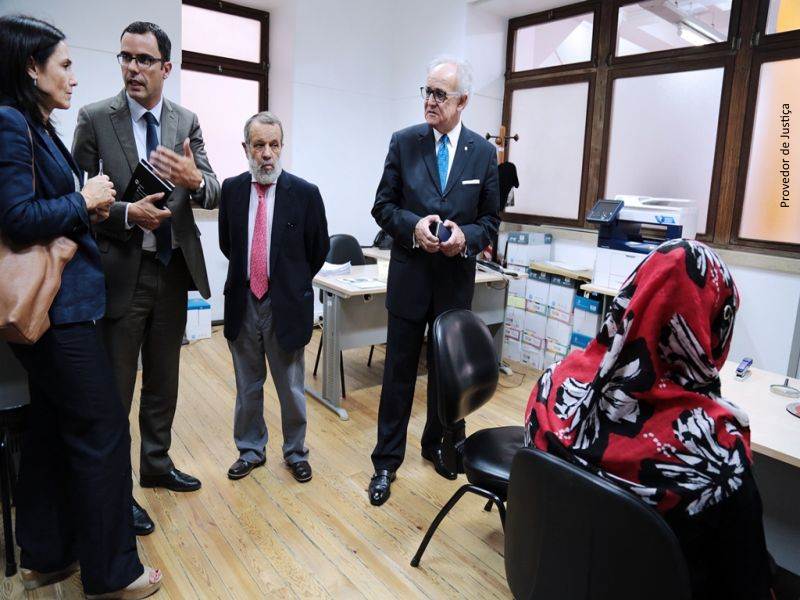 Elena Arce, Pedro Calado, Francisco Fernández Marugán y José de Faria Costa en una sala junto a una migrante de espaldas