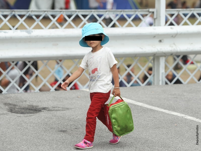 Niña inmigrante con mochila cruzando fronera