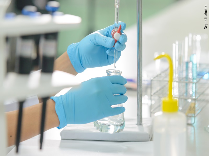 Manos con guantes en un laboratorio trabajando con probetas
